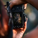 A person photographs the historic Eltz Castle using a digital camera, blending history and technology.