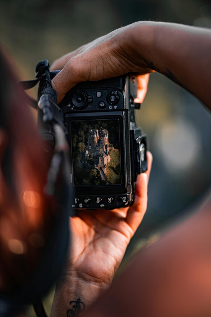A person photographs the historic Eltz Castle using a digital camera, blending history and technology.